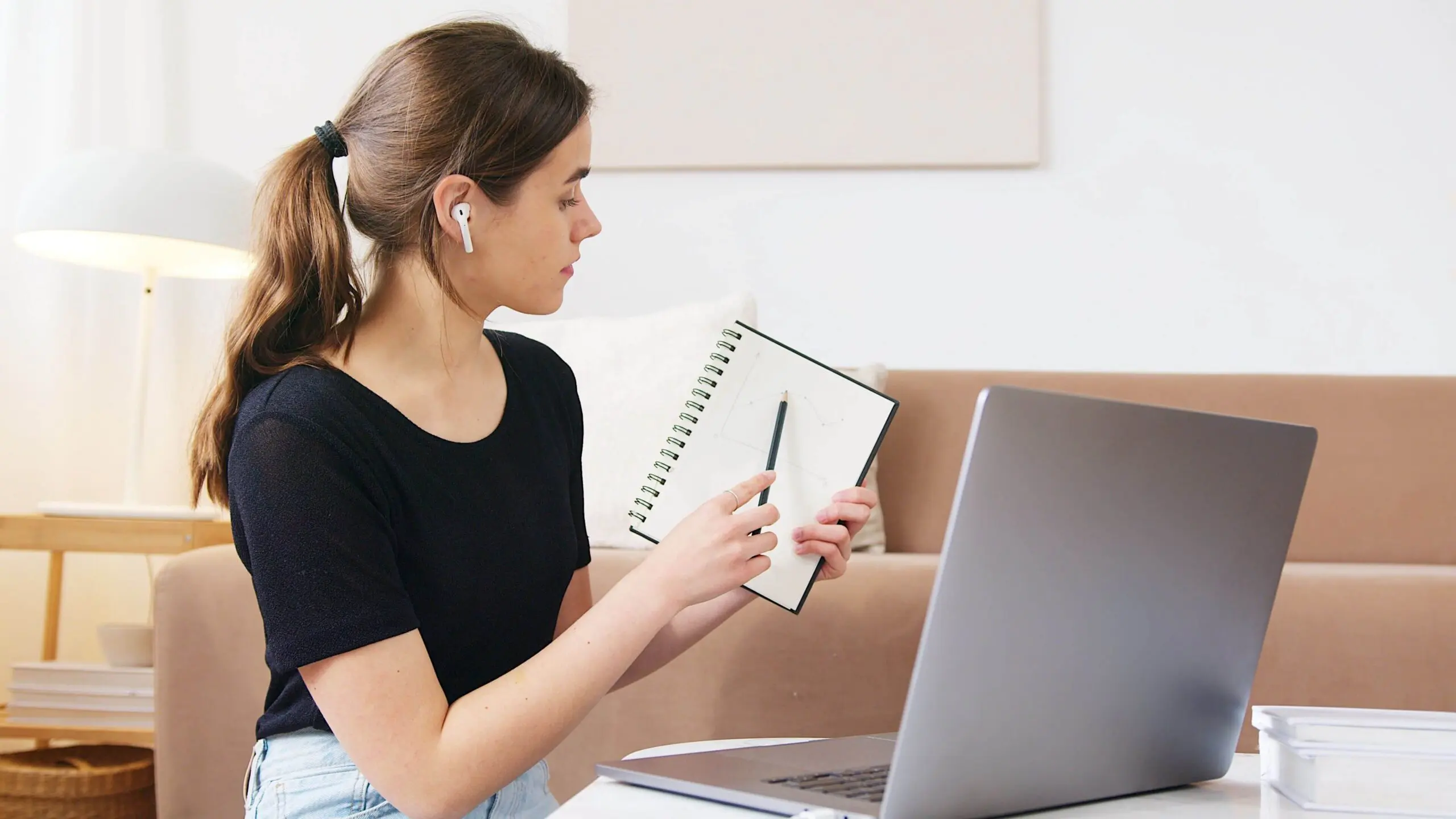 Student taking notes from a laptop during an online training course